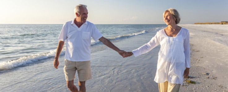 retired couple holding hands at beach