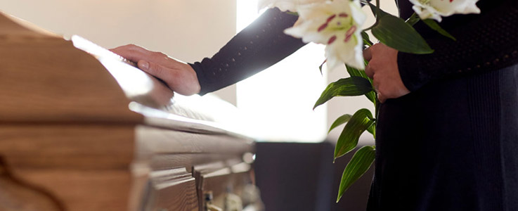 person lying hand on funeral casket