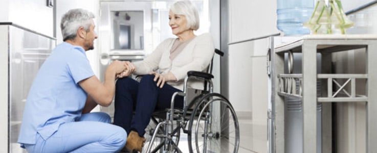 doctor kneeling next to patient in wheelchair