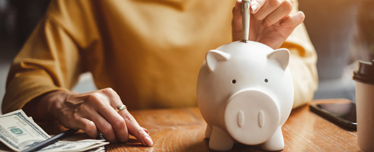 woman placing savings into piggy bank