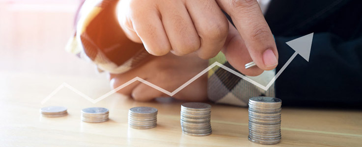 businessman stacking coins with rising stock market arrow
