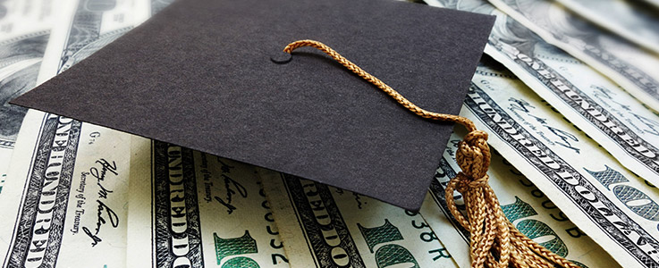 graduation cap on top hundred dollar bills