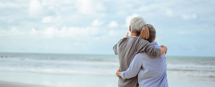 retired couple embracing at ocean
