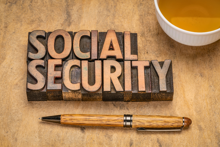 Wooden block letters spelling "Social Security" on a wooden table, symbolizing the different types, payments, and eligibility