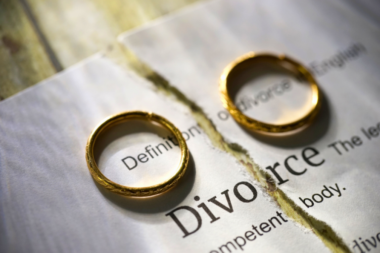 Wedding rings on top of a ripped divorce paper, representing the impact of divorce on annuities